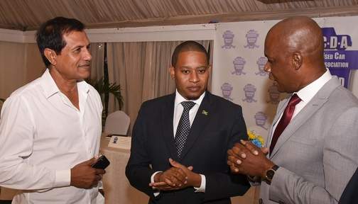 Minister of State in the Ministry of Industry, Commerce, Agriculture and Fisheries, Floyd Green (centre), listens as President of the Jamaica Used Car Dealers Association (JUCDA), Lynvalle Hamilton, makes a point before the start of the entity's Annual General Meeting on Thursday (February 27) at Terra Nova All-Suite Hotel in Kingston. Also sharing in the conversation (at left) is Managing Director of Carland Investment Ltd, Tariq Malik. (Photo: JIS)